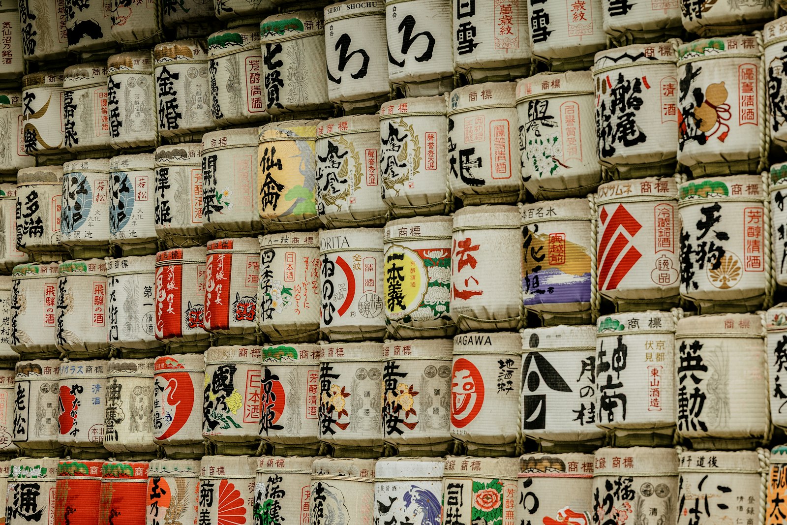 書道の文字が描かれた酒樽が積まれた壁